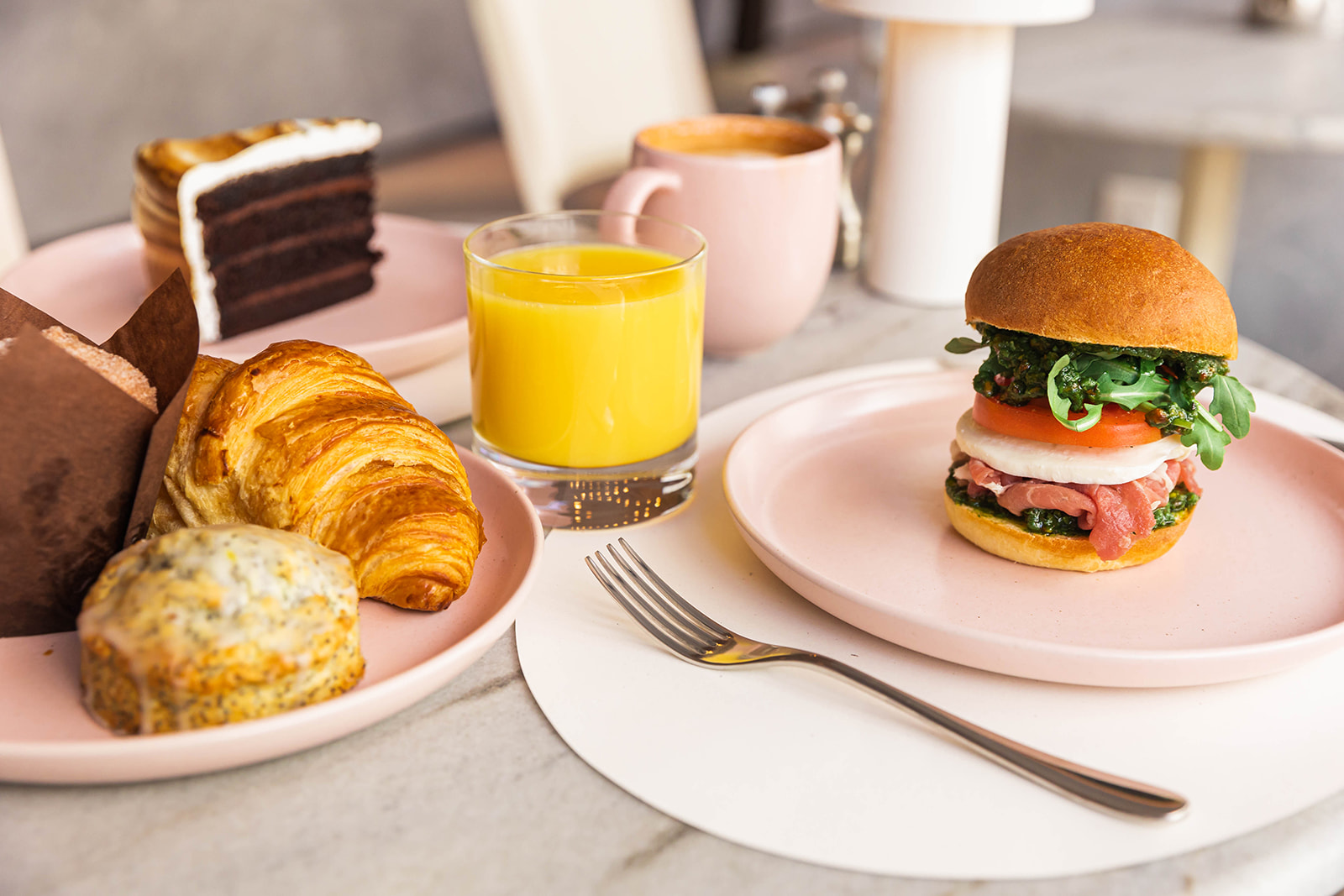 Pastries and a Cheese, coffee, orange juice & Bacon Sandwich photographed from the side.